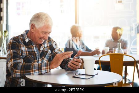 Sharing a giggle with the one I love. a senior man using his phone in a cafe. Stock Photo