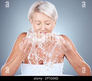 Water, splash and senior woman in studio for natural, cosmetic and facial routine for hygiene. Health, wellness and elderly lady doing clean, organic Stock Photo