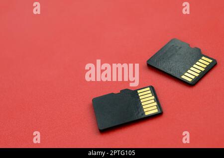 Two small micro SD memory cards lie on a red background. A small and compact data and information store Stock Photo