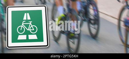 new german traffic sign indicating prioritized bicycle highway in front of a blurred background with different bicycles on a road Stock Photo