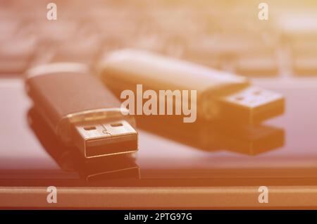 USB flash cards lying on black laptop case in front of his keyboard. Virtual memory storage with USB output Stock Photo