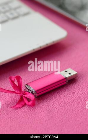 Brilliant pink usb flash memory card with a pink bow lies on a blanket ...