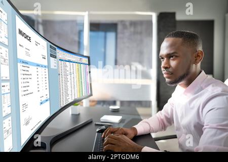 Looking At Invoice And Spreadsheet On Computer At Work Stock Photo