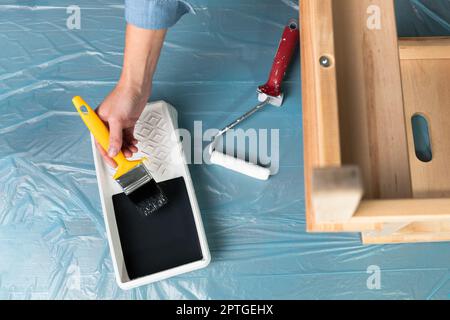 Young women preparing to restore a stepladder for children as a hobby house improvement. On a covered table. Stock Photo