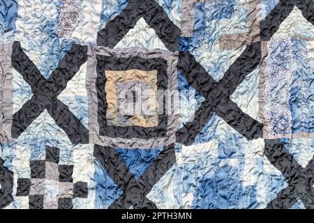 part of wrinkled hand-stitched patchwork quilt from pieces of various silk fabrics sewn in convergence technique Stock Photo