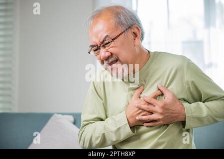 Senior man bad pain hand touching chest having heart attack, Asian older man have congenital disease suffering from heartache alone at home his heart Stock Photo