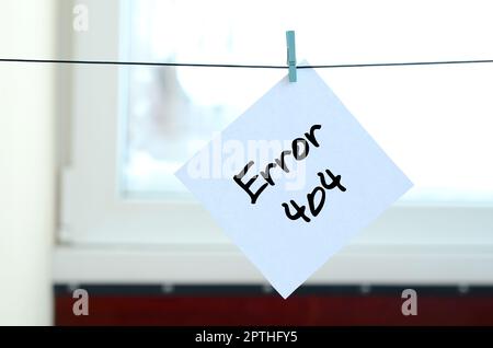 Error 404. Note is written on a white sticker that hangs with a clothespin on a rope on a background of window glass Stock Photo