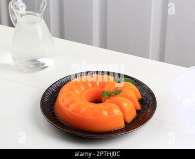 Mango Orange Pudding on Black plate with Mint Leaf, on White Table Stock Photo