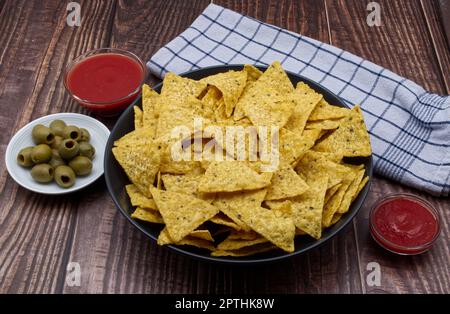 Nachos in a bowl with tomato sauce and olives. Tortilla chips isolated on white background. Stock Photo