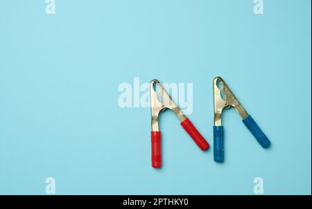 Metal crocodile clip for cigarette lighter wires on a blue background, copy space Stock Photo