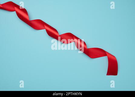 Twisted silk red ribbons for decoration on a blue background, top view Stock Photo