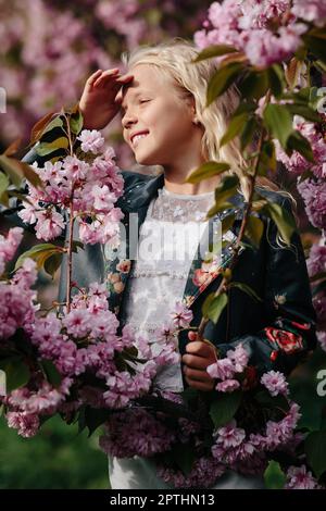 portrait of a beautiful little child girl with sakura flowers on a sunny spring day Stock Photo