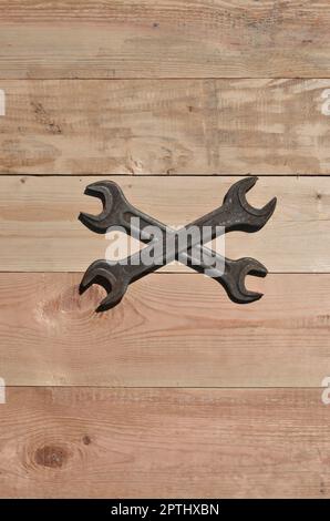 A few rusty spanners on a wooden background. Obsolete household tools made of rusty metal lie on a wooden table in a workshop. The concept of repair a Stock Photo