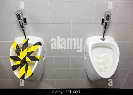 Munich, Germany. 27th Apr, 2023. A urinal blocked with yellow and black tape is seen in a men's restroom. Credit: Peter Kneffel/dpa/Alamy Live News Stock Photo