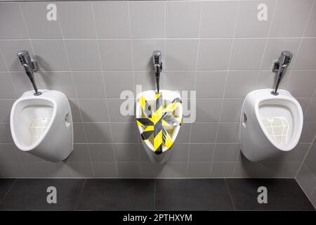 Munich, Germany. 27th Apr, 2023. A urinal blocked with yellow and black tape is seen in a men's restroom. Credit: Peter Kneffel/dpa/Alamy Live News Stock Photo