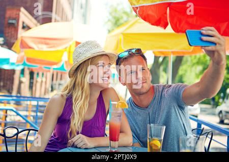 Capturing the moment. a young couple taking a selfie while sitting at an outdoor cafe. Stock Photo