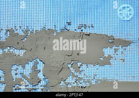 The texture of the wall, covered with gray foam polystyrene plates, covered with a blue reinforcing mesh and covered with a mixture for gluing it. Sta Stock Photo