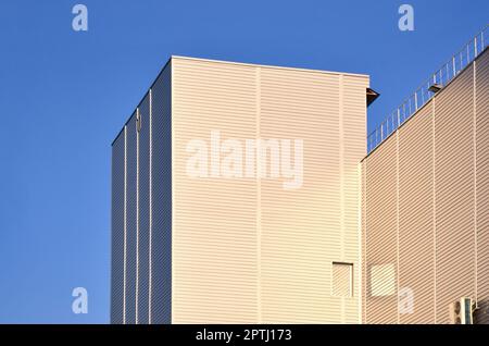 Photo of industrial high-rise building with perfect quality siding in sunlight. The huge building is completely covered with a striped metallic emboss Stock Photo