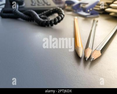 Three pencils lie sharply sharpened next to folders with sheets of paper and documents on the working business desk in the office. Stationery. Stock Photo
