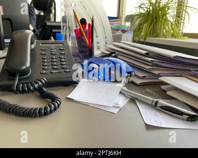Black landline telephone with a tube, buttons and a wire on the work table at the office desk with office supplies. Business work. Stock Photo