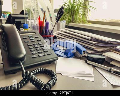 landline phone in the office on the table. black handset with buttons and display. communications in the office. Stock Photo