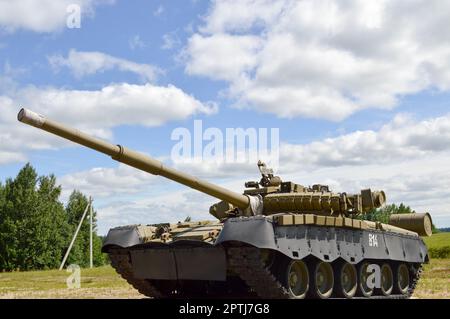 A large green military metal armored deadly dangerous iron Russian Syrian battle tank with a gun turret and a goose is parked parked against a blue sk Stock Photo