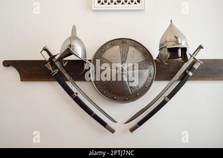 Old ancient medieval sharp dangerous combat captured swords, sabers, edged weapons and armor, shields. Stock Photo