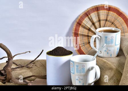 Present a cup of black tea with garden-fresh organic tea leaves in a beautifully designed can - perfect for advertising, packaging Stock Photo