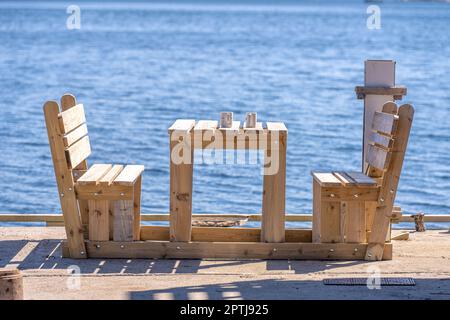 Two mugs on a table by benches by the sea Stock Photo