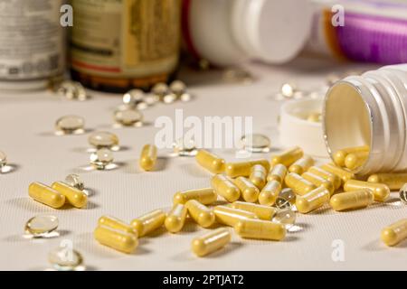 Yellow pills for oral use on a white background. Medications in the form of tablets in a white plastic jar. Concept of healthcare and medicine Stock Photo