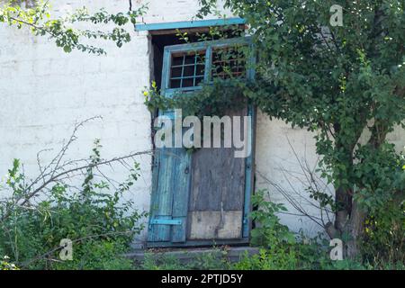 hacked old wooden door in an abandoned house in a village Stock Photo