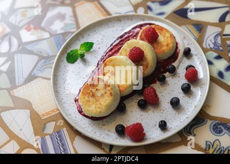 Cheesecakes served on plate with berries, cream and sugar powder ready for eating in restaurant Stock Photo