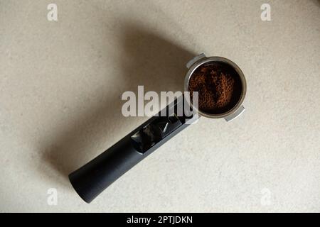 Top view of metal holder with plastic handle from the coffee machine with ground coffee inside. Coffee horn and coffee filter holder. Stock Photo