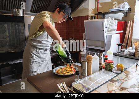 Professional chef finished cooking of dish and add the sauce in restaurant kitchen Stock Photo