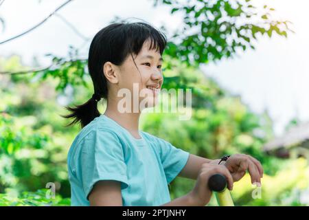 Cheerful child girl playing on playground in the park. Healthy summer activity for children. Stock Photo