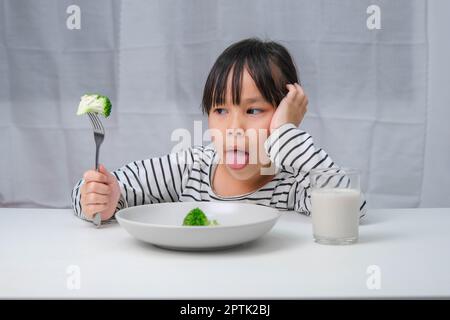 Children don't like to eat vegetables. Cute Asian girl refusing to eat ...