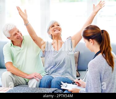 Overjoyed at her test results. A doctor explaining positive test results to an overjoyed senior patient and her husband Stock Photo