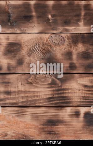 The texture of the scorched wooden wall. Wall of smooth orange long wooden boards with a specific black texture of frying Stock Photo