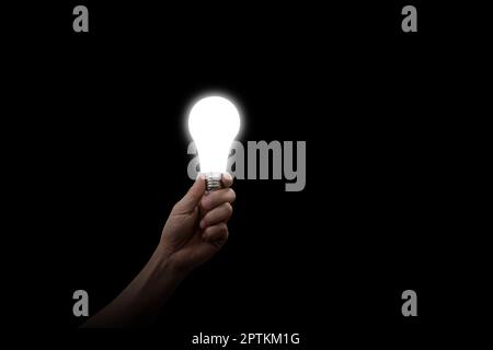 Male hand holding LED Bulb with Lighting on dark background Stock Photo