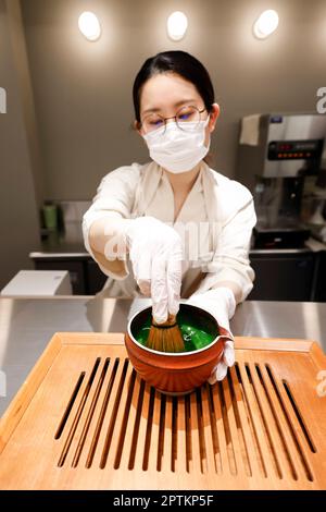 April 26, 2023, Tokyo, Japan: A woman prepares green tea Matcha latte for clients at the new mix-use complex Haneda Airport Garden, located in front of Haneda Airport Int. Terminal 3. The Haneda Airport Garden complex has finally opened after a three-year delay caused by the pandemic. The complex includes a 1,717-room airport hotel with a natural hot spring spa, MICE-ready event space and meeting rooms that aim to strengthen Haneda Airport's position as a 24-hour international hub airport. Additionally, the complex has around 80 commercial establishments that offer a variety of retail shops, e Stock Photo