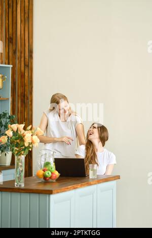 Two beautiful students making video conference call sitting in the kitchen Stock Photo