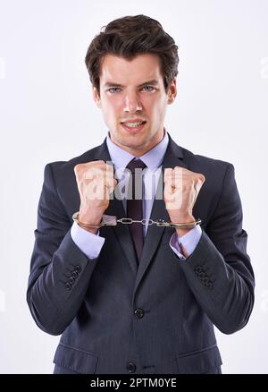 I need to break free of the corporate shackles. Studio shot of a handsome young businessman in handcuffs Stock Photo