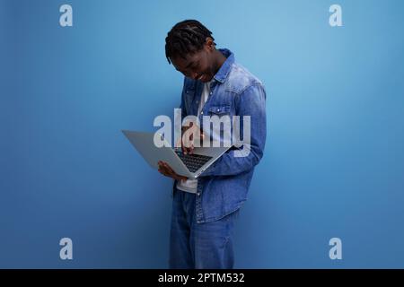 successful freelancer american man with dreadlocks in denim jacket works remotely using laptop Stock Photo