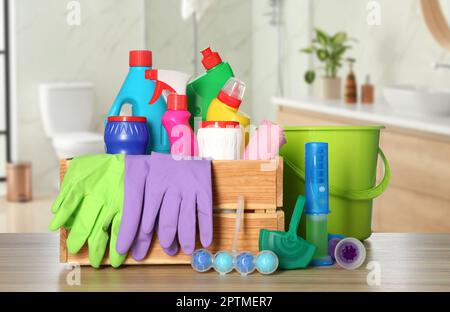Different toilet cleaning supplies on wooden table in bathroom