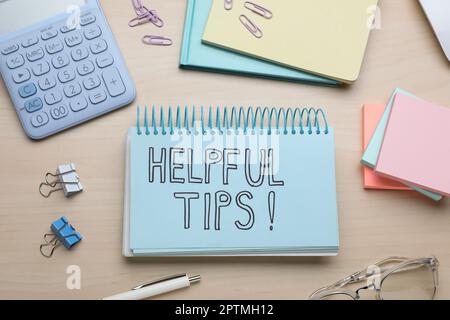 Notebook with phrase Helpful Tips and stationery on wooden table, flat lay Stock Photo
