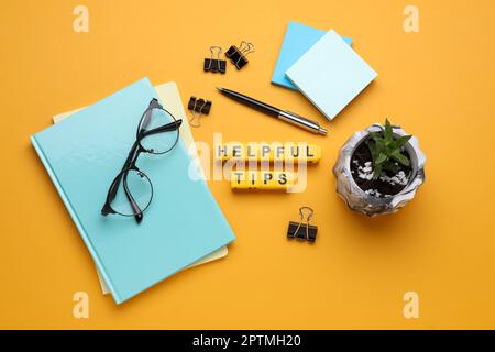 Flat lay composition with phrase Helpful Tips made of yellow cubes on orange background Stock Photo