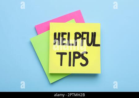 Paper note with phrase Helpful Tips on light blue background, top view Stock Photo
