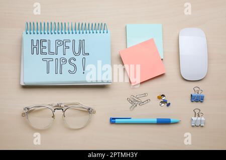 Notebook with phrase Helpful Tips and stationery on wooden table, flat lay Stock Photo