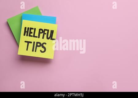 Paper note with phrase Helpful Tips on pink background, top view. Space for text Stock Photo