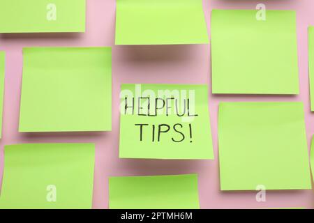 Paper note with phrase Helpful Tips on pink background Stock Photo